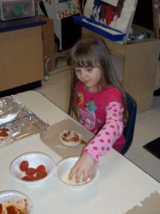Girl reaching into bowl of cheese for her pizza that she is making