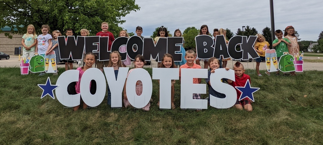 students with sign, welcome back coyotes