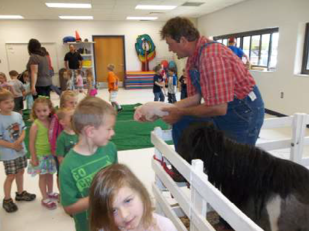 Students in line to see farm animals that in pens in the activity room.